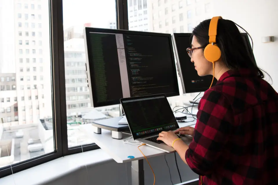 Desenvolvedora escrevendo código em dois monitores
