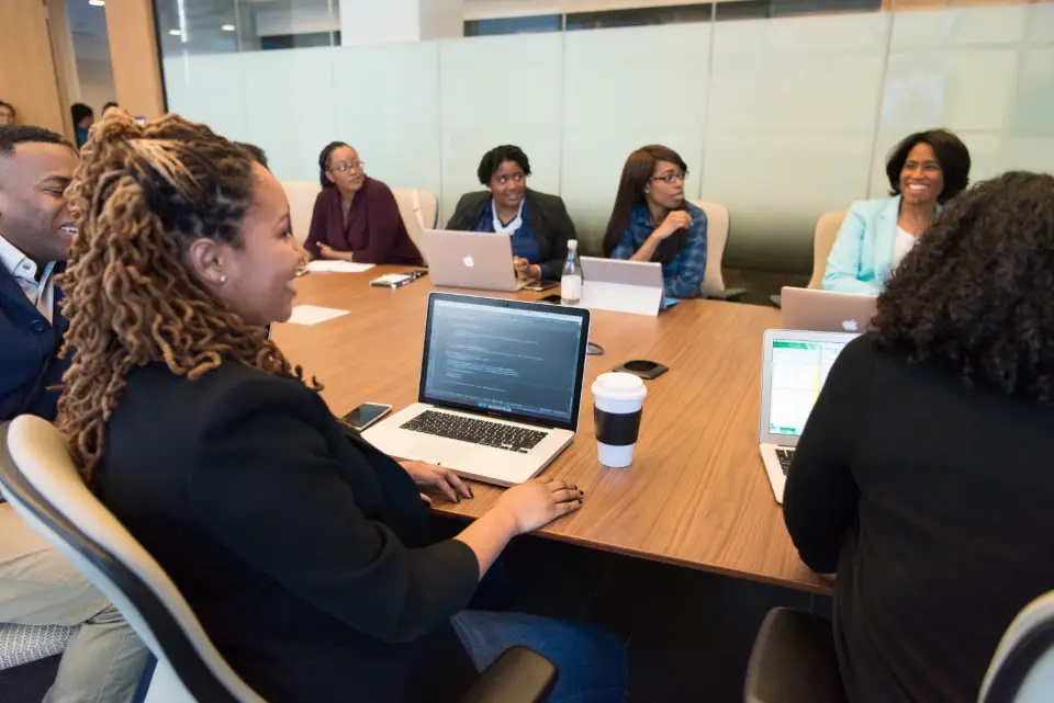 Equipe reunida em volta de uma mesa com notebooks